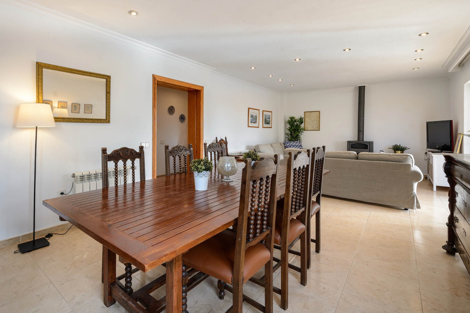Formal dining table with a wood-burning stove and open-plan living beyond, Villa Suki, Ibiza.