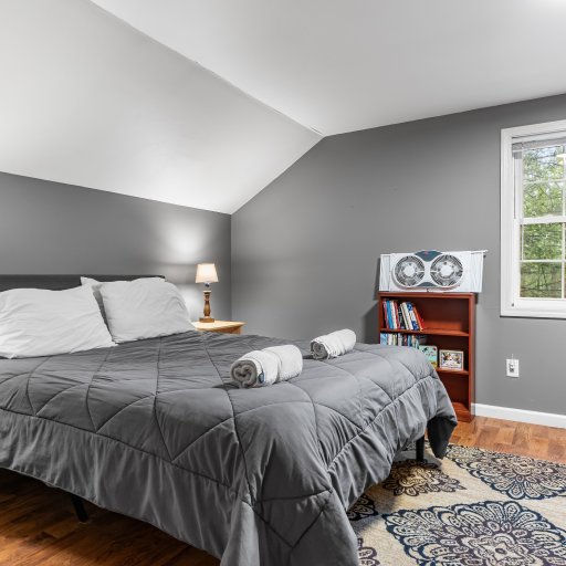 Upstairs queen bedroom with a window fan and a shelf of books