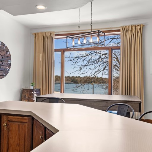 Counter-height dining for six with a Round Lake view — arched window facing the marina and Charlevoix lighthouse.