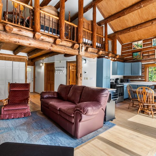 Great room under exposed log beams, with the loft overhead