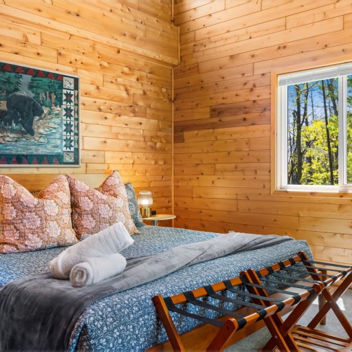 King primary suite under vaulted cedar ceilings