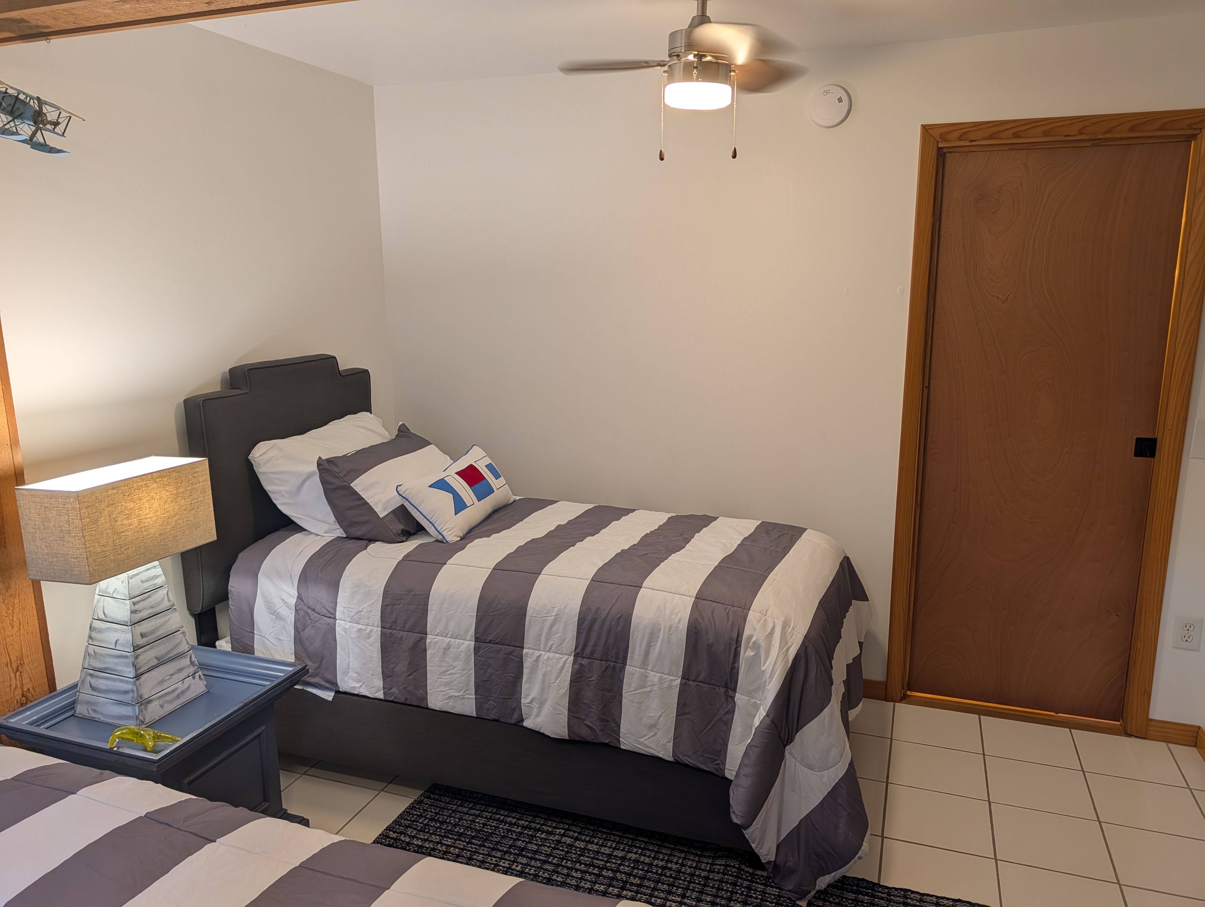 BEDROOM #4 (SECOND FLOOR):  Features 2 twin size beds, a dresser, mirror, nightstand, lamp, ceiling fan, and a clothes rack.