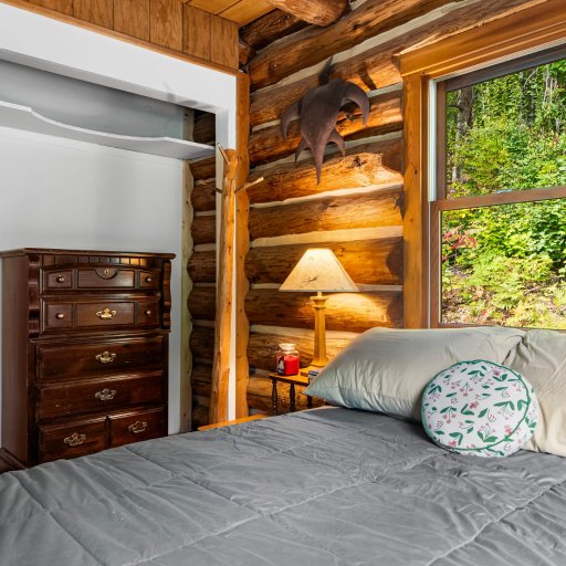 Main-floor bedroom with dresser and wooded window view