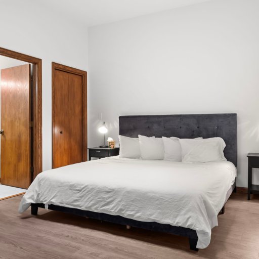 Bedroom 1: King bed behind French doors — quiet, private, sized for true rest after a Charlevoix sightseeing day.