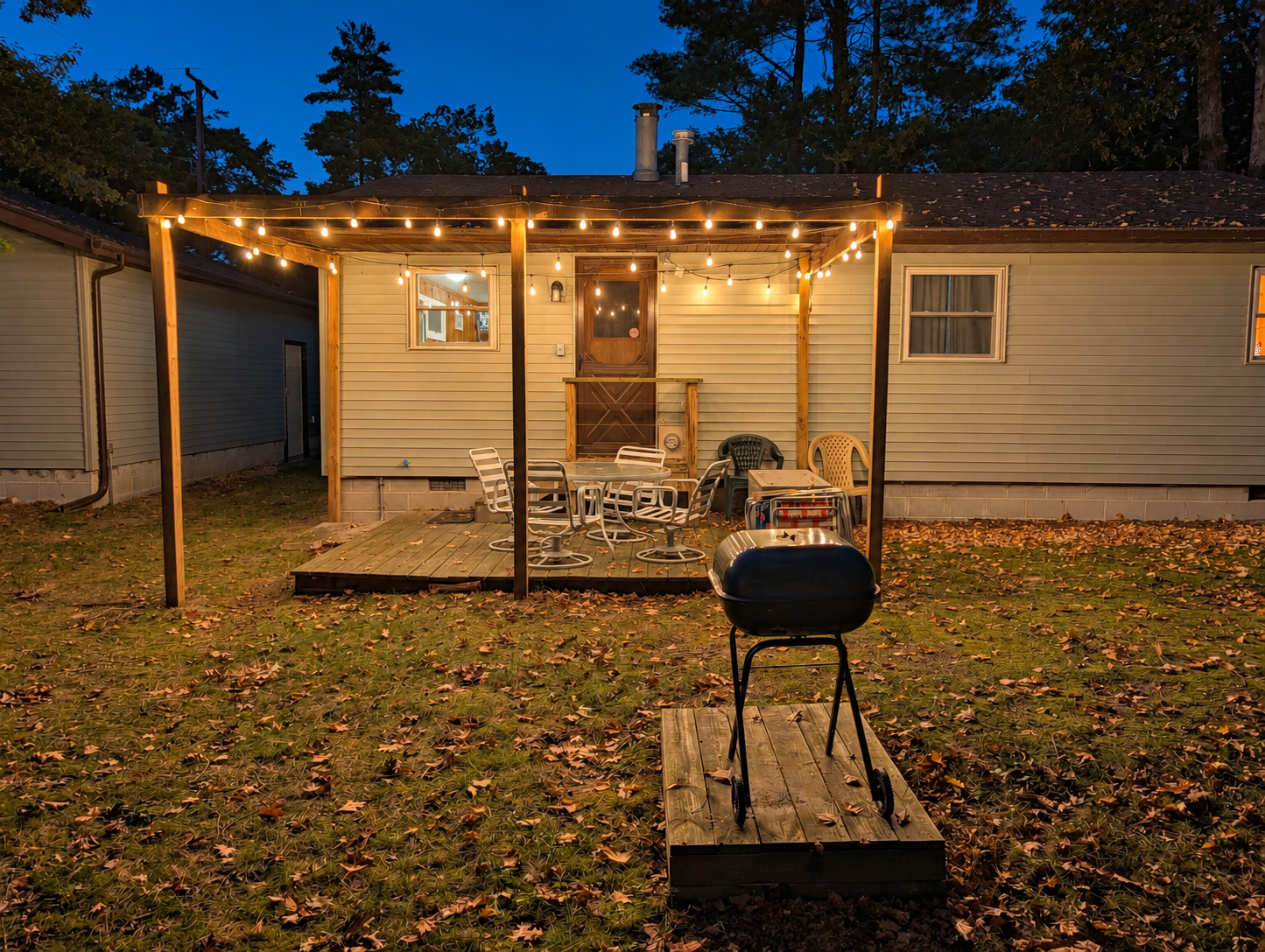 OVERVIEW:  The back of the cottage at night, highlighting the charcoal grill, the backyard deck, and the outdoor furniture.