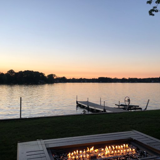 Gas fire pit on the lawn with the dock and lake beyond