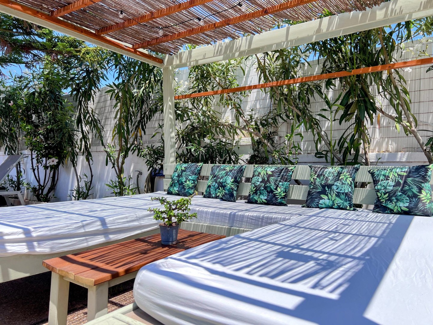 The seats nobody wants to leave. Covered outdoor lounge with tropical-print cushions and daybeds, Villa Kiku garden.