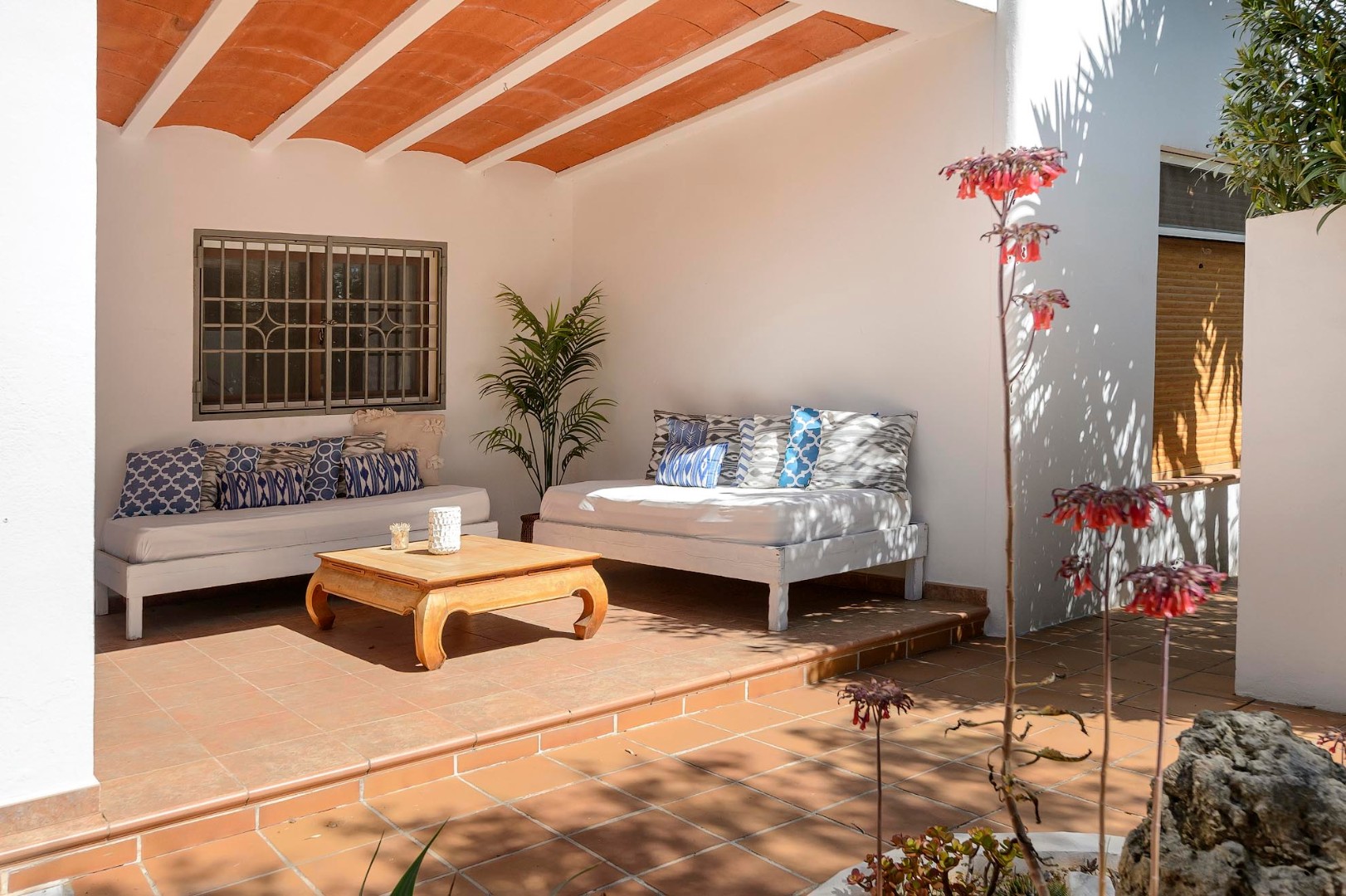 Shaded terrace lounge with daybeds under a beamed ceiling, Villa Mika, Ibiza.