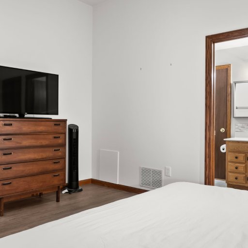 Bedroom 1 with smart TV on the dresser — opens onto a Jack-and-Jill bath shared with Bedroom 2.