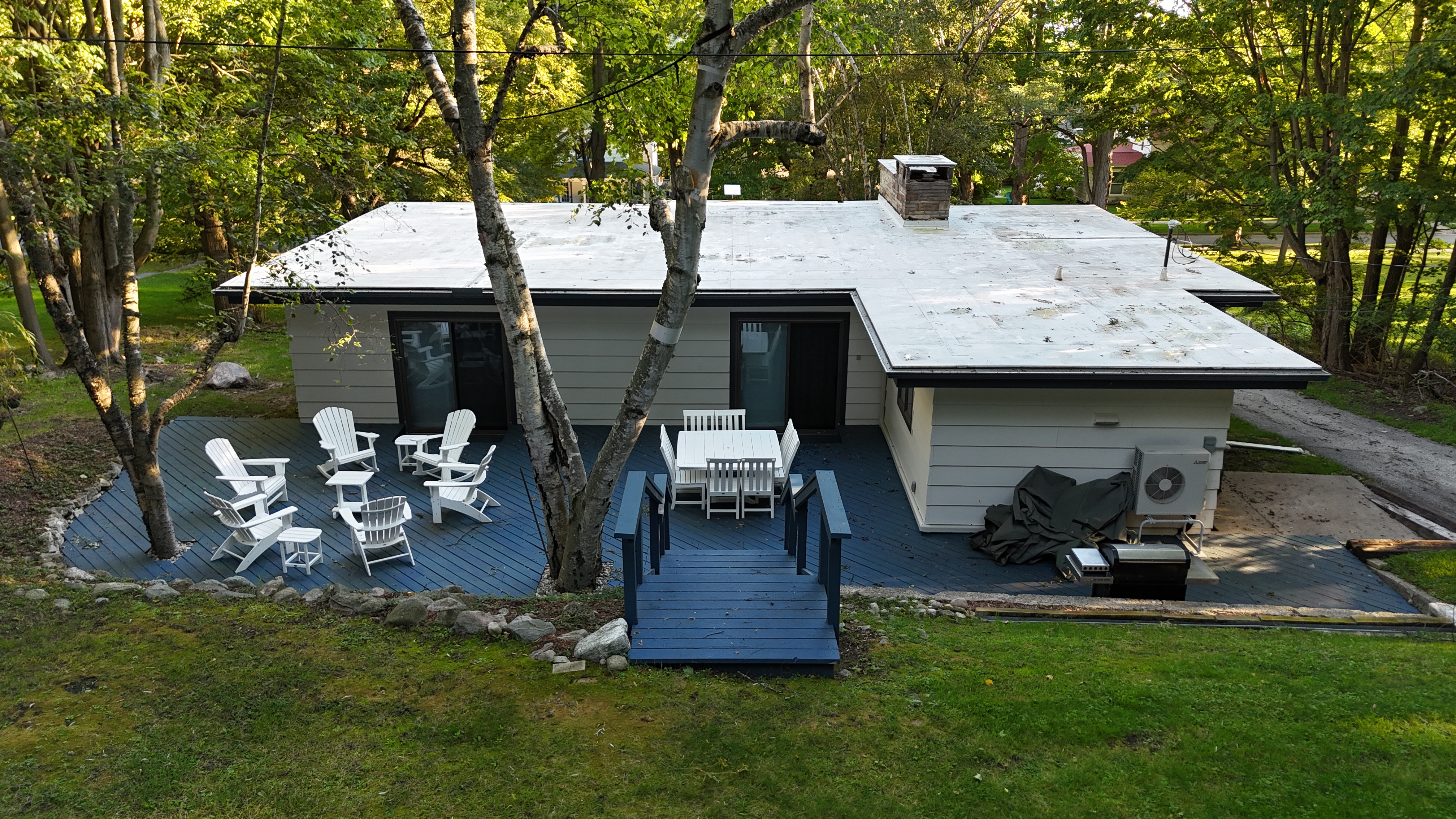OVERVIEW:  The beautiful backyard deck, featuring a propane grill, outdoor dining furniture, and Adirondack chairs with tables.